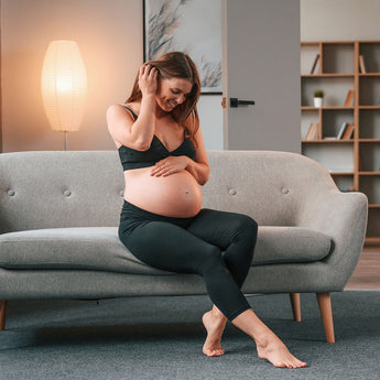 Pregnant woman staring at her belly in the living room