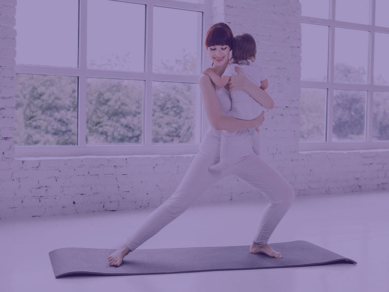 Mother doing yoga with toddler in hands