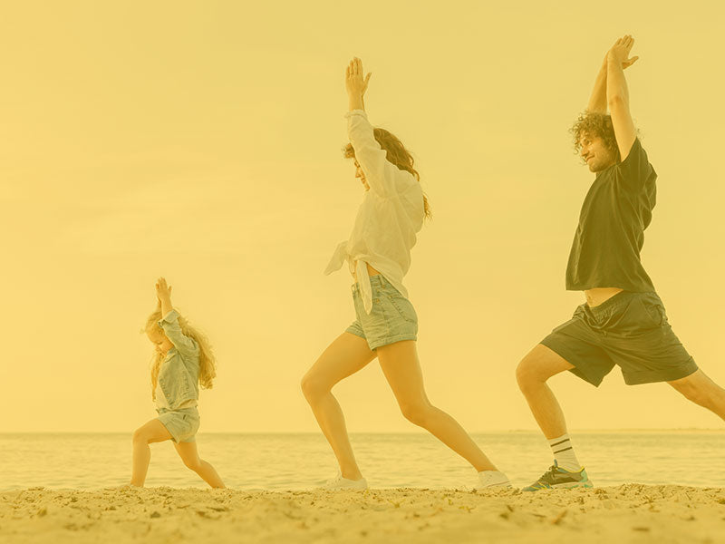 Family exercising in the sand by the beach with clothes on