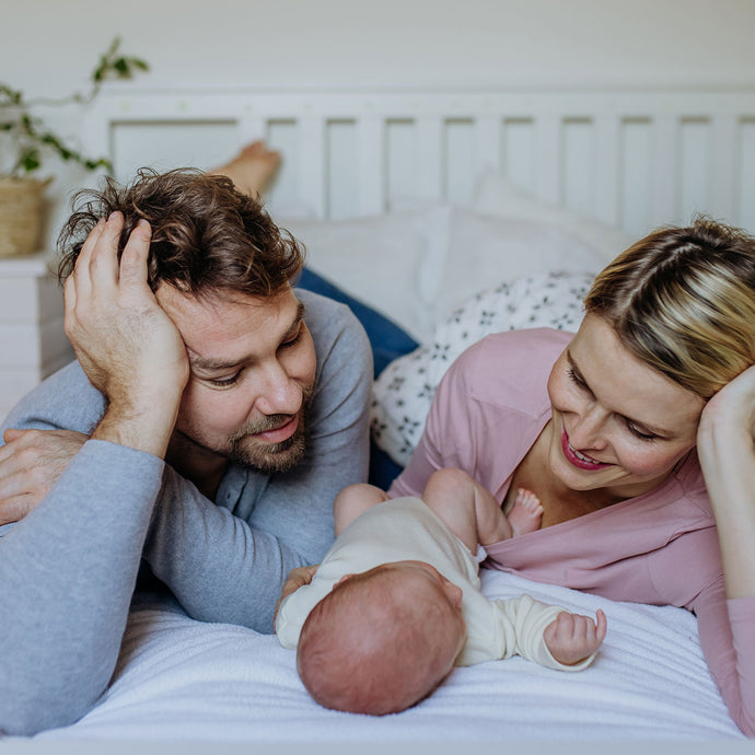 Couple staring at their baby in bed