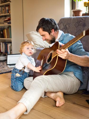 Father and son at home playing guitar together