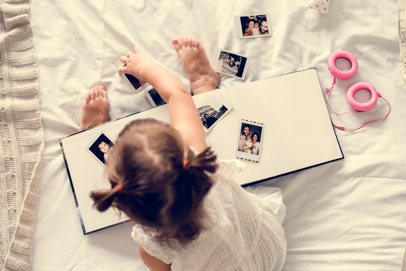 Girl toddler playing with photo album in the bed