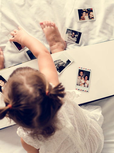 Girl toddler playing with photo album in the bed